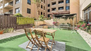 A courtyard with a wooden table and chairs, surrounded by a wooden fence and potted plants. - Stayshort - Warm Spacious 3 Bedroom in The Greens That Sleeps 8 (Dubai)