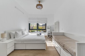 Une chambre avec un grand lit, un bureau et une fenêtre donnant sur un paysage verdoyant.