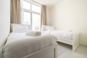 A hotel room with two beds, a large window with curtains, and a white color scheme. - Stayshort - Modern 3 BR Villa in Damac Hills 2 With Garden That Sleeps 6 (Dubai)
