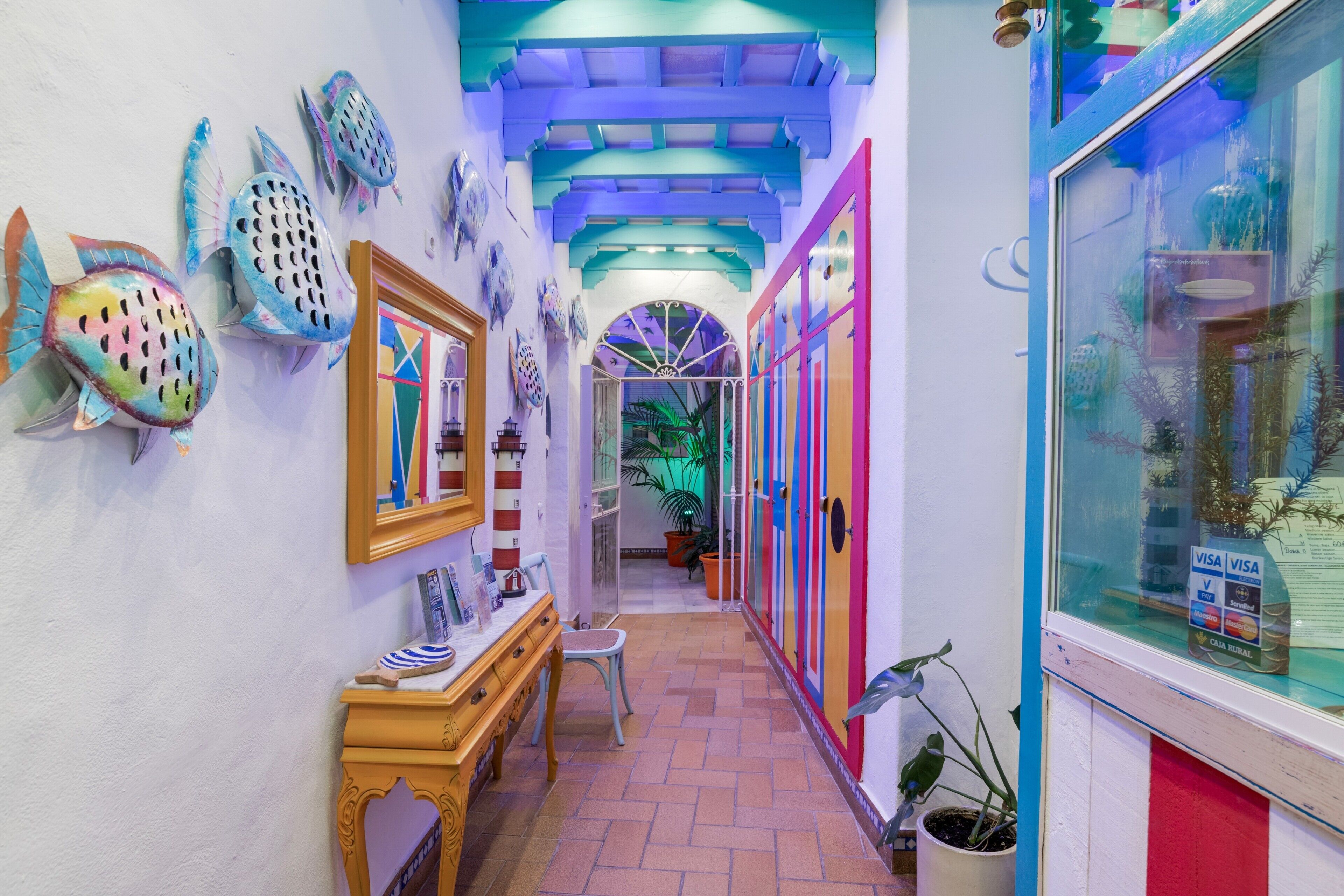 A hallway with colorful fish wall art, a wooden bench, and a potted plant.
