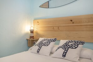 Een slaapkamer met een houten hoofdbord, een wandlamp en twee kussens met een bladmotief.