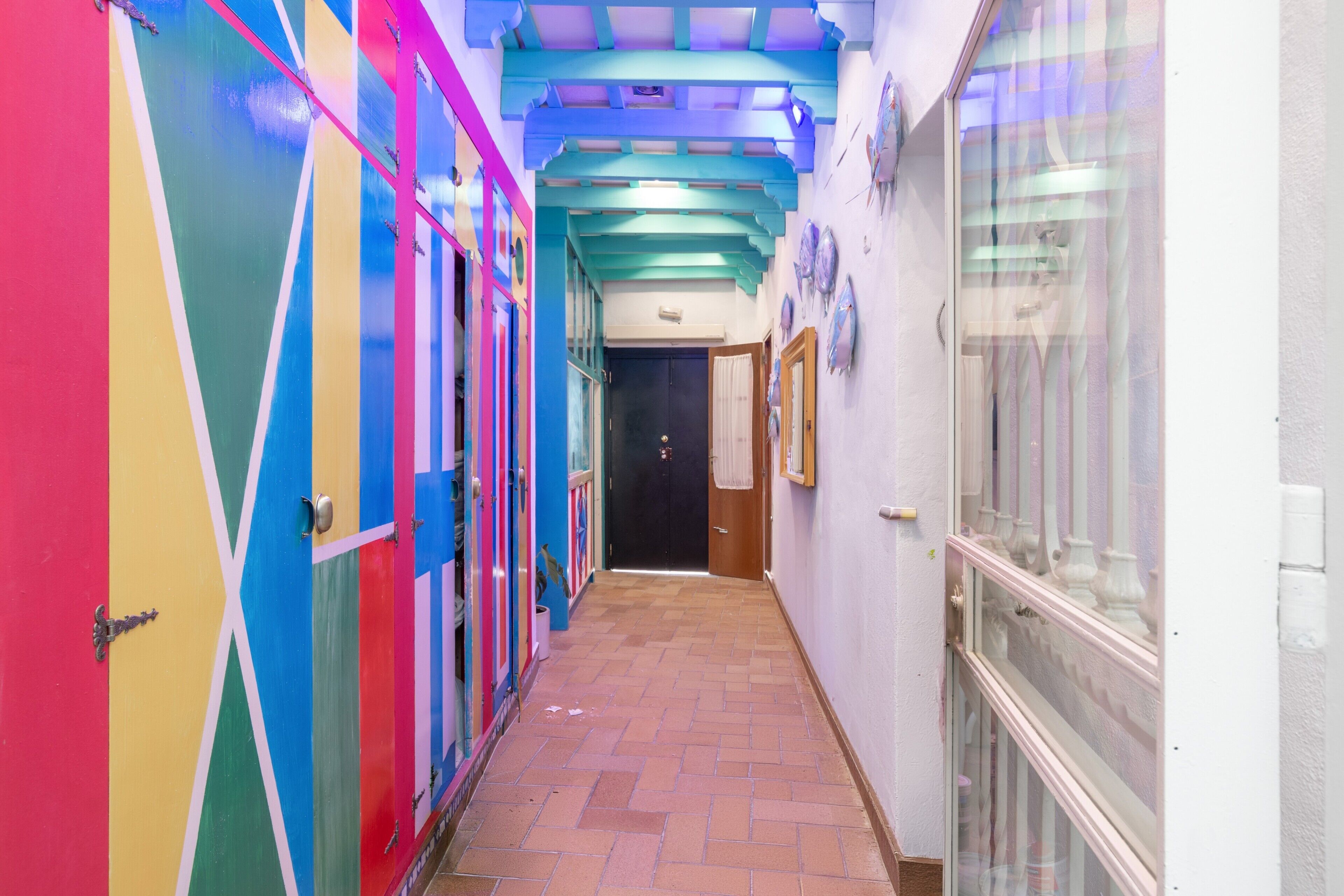 A hallway with colorful lockers, a tiled floor, and a door at the end.