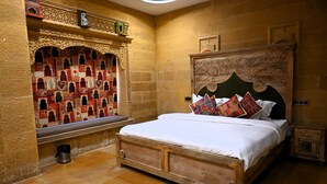 Una habitación tradicional con cama, decoración de pared detallada y un mueble pequeño.