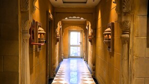 Un pasillo con suelo de cuadros, columnas ornamentales e iluminación empotrada en el techo.