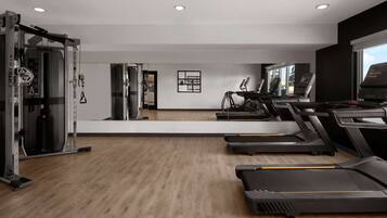 A gym with treadmills, a weight machine, and a mirror wall.