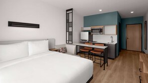 Une chambre d’hôtel équipée d’un lit, d’un bureau avec une chaise, d’un four à micro-ondes et d’un lavabo.