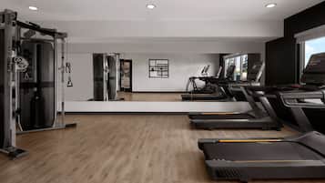 A gym with treadmills, a weight machine, and a mirror wall.