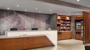 A hotel reception area with a wooden reception desk, a wall with text, and a shelf with snacks. - Near Truist Park + Free Breakfast & Indoor Pool (Atlanta)