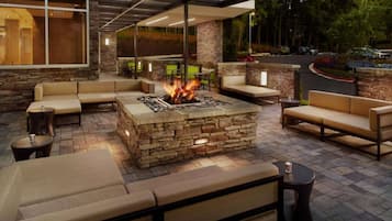 An outdoor patio with stone fire pit, cushioned seating, and a view of the street.