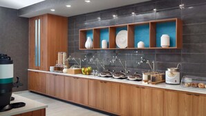 A modern kitchen with wooden cabinets, a breakfast bar, and a variety of food items. - Steps from Truist Park + Free Breakfast & Pool (Atlanta)