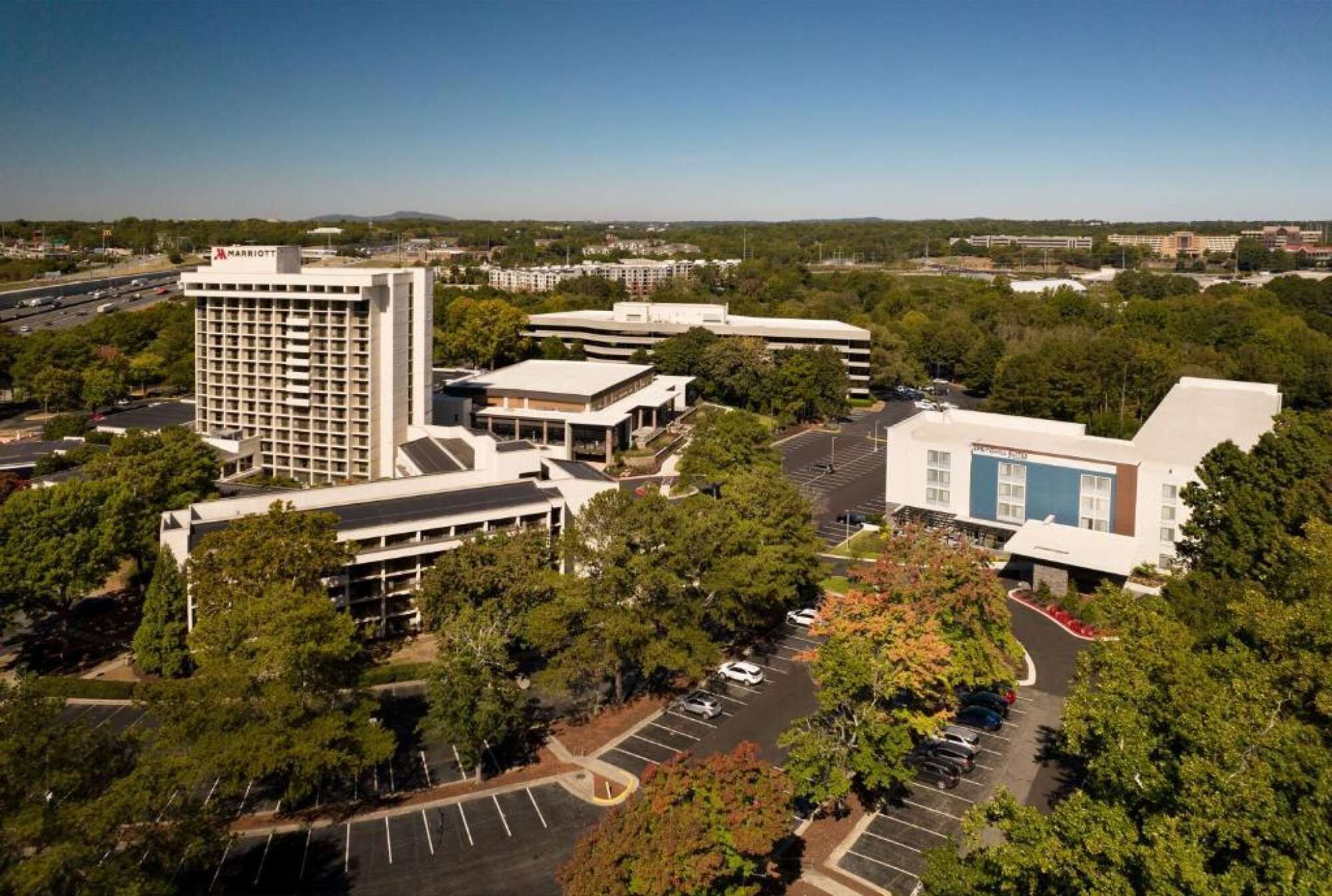 A Marriott hotel with a modern design, surrounded by trees and a parking lot.