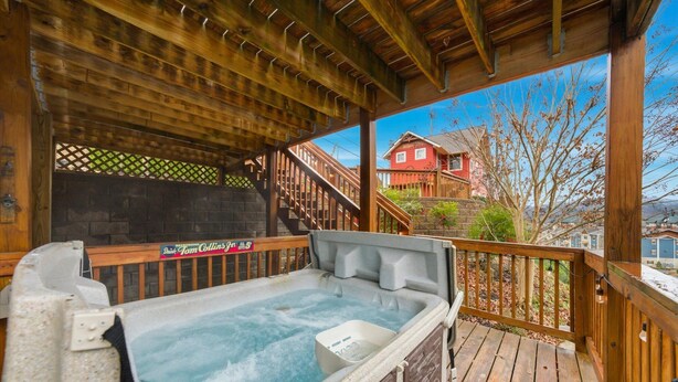 Ein Whirlpool auf einer Holzterrasse mit Blick auf ein rotes Haus und einer darüberführenden Treppe.