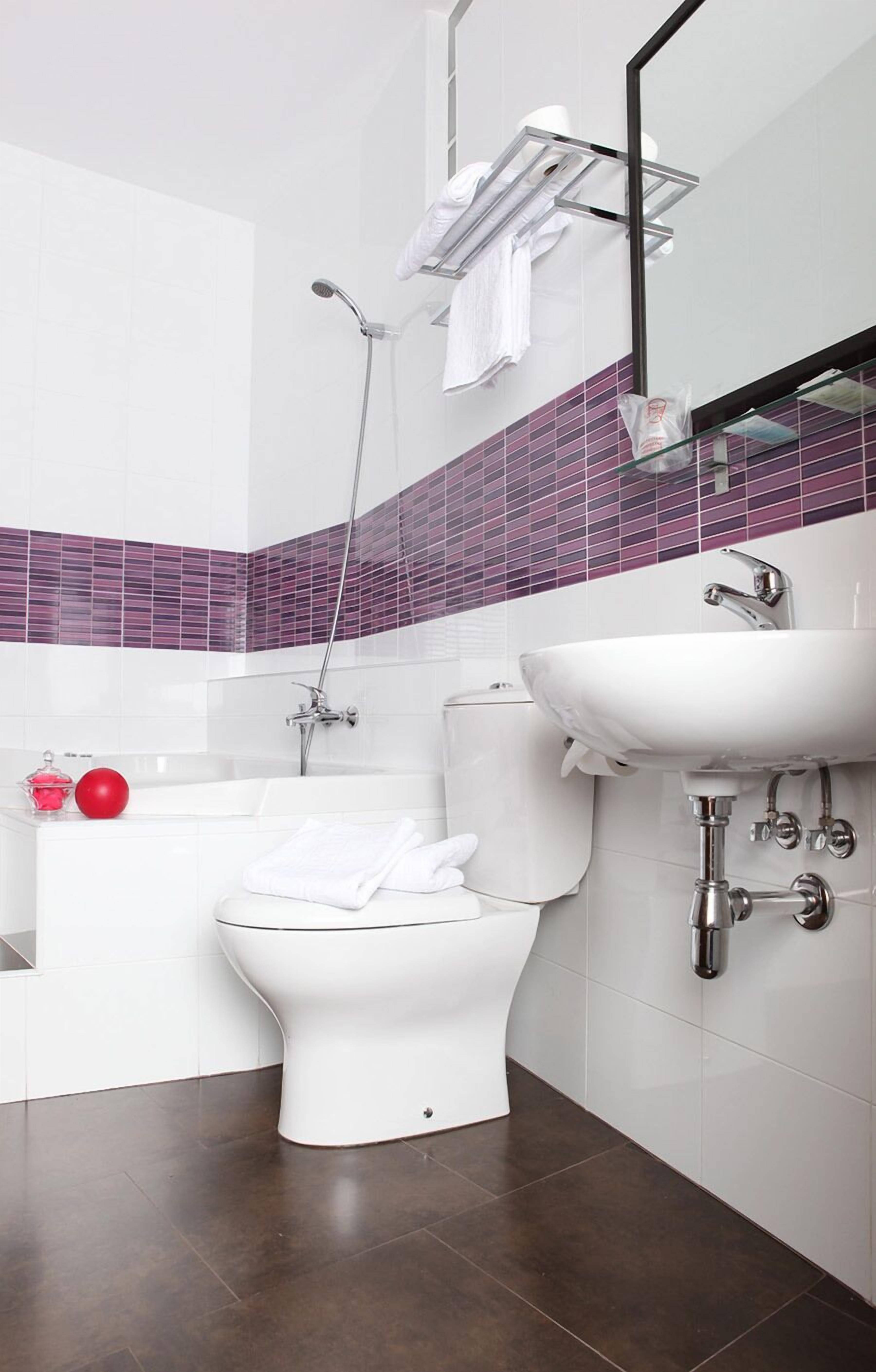 A modern bathroom with a white toilet, a bathtub, and a sink.