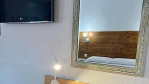 A compact kitchenette with a wooden countertop, a black chair, a built-in TV, and a mirror with a wooden frame. - Hostal Real (San Juan del Puerto)