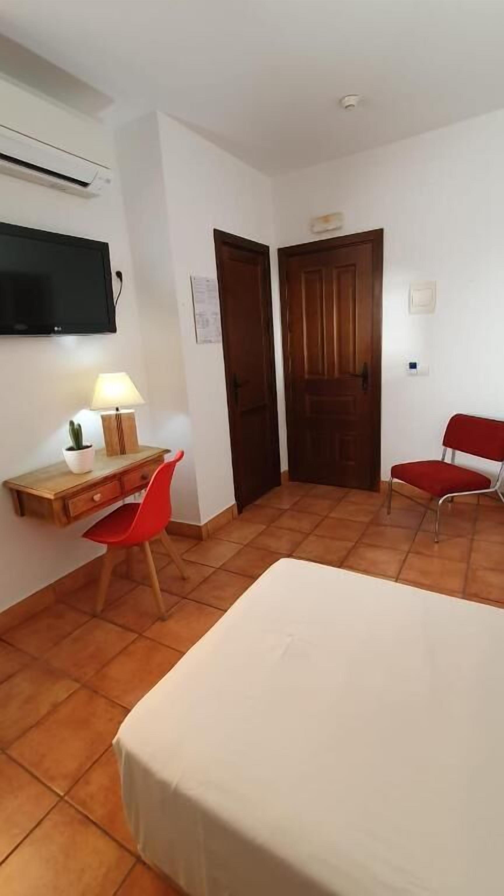 Una habitación pequeña y limpia con una cama, un escritorio y dos sillas.