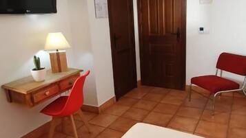 Una habitación pequeña y limpia con una cama, un escritorio y dos sillas.