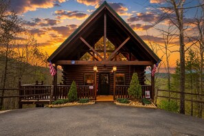 A log cabin with a porch, American flags, and a sign indicating ADA compliance. - Nascar Nation: Where Every Stay Wins (Sevierville)