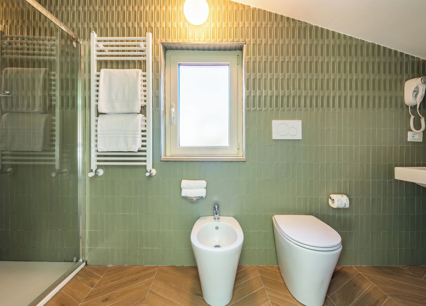 Une salle de bain équipée d’une douche, d’un bidet, de toilettes, d’un porte-serviettes et d’une fenêtre.