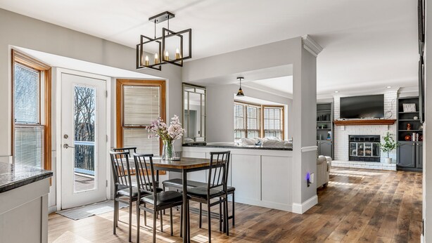 A spacious kitchen with a dining area, wooden flooring, and a modern chandelier. - 5BR Group Retreat | Hot Tub, Deck & Workspace (Saint Charles)