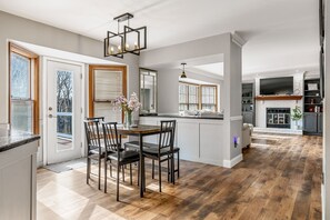 Een ruime keuken met een eethoek, houten vloeren en een moderne kroonluchter.