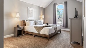 A bedroom with a bed, bedside lamps, a window with curtains, and a nightstand. - 5BR Group Retreat | Hot Tub, Deck & Workspace (Saint Charles)