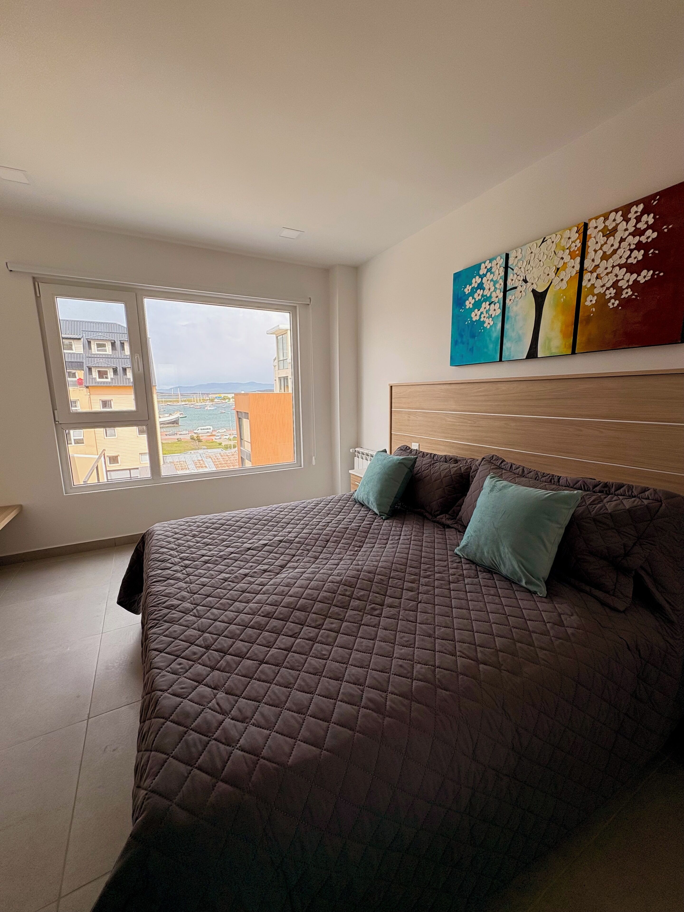 Ein Schlafzimmer mit einem großen Bett, Meerblick und einem Bild an der Wand.