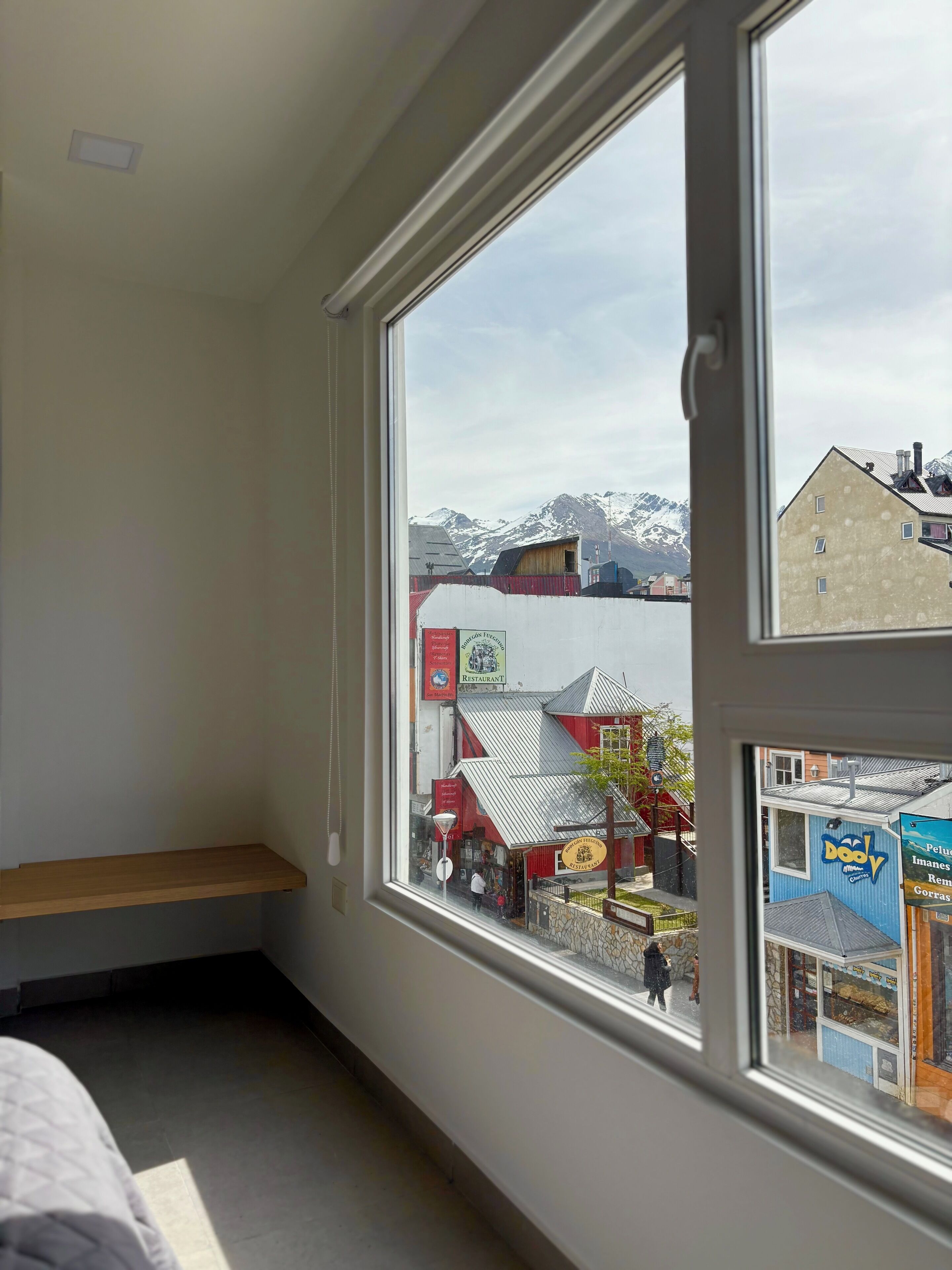 A room with a large window overlooking a town with buildings and mountains.