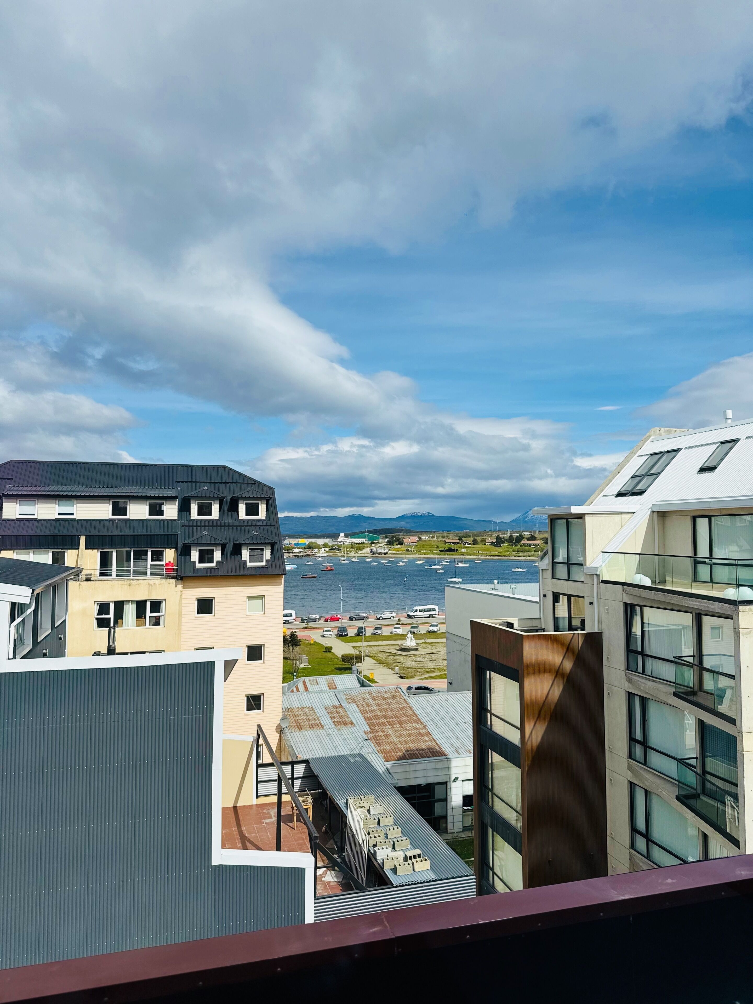 A modern building with multiple floors, large windows, and a view of a body of water with boats.