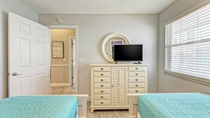 A bedroom with two beds, a dresser, a television, and a window with blinds. - Steps to Manatee Beach, Pool, and Private Sun Deck (Holmes Beach)