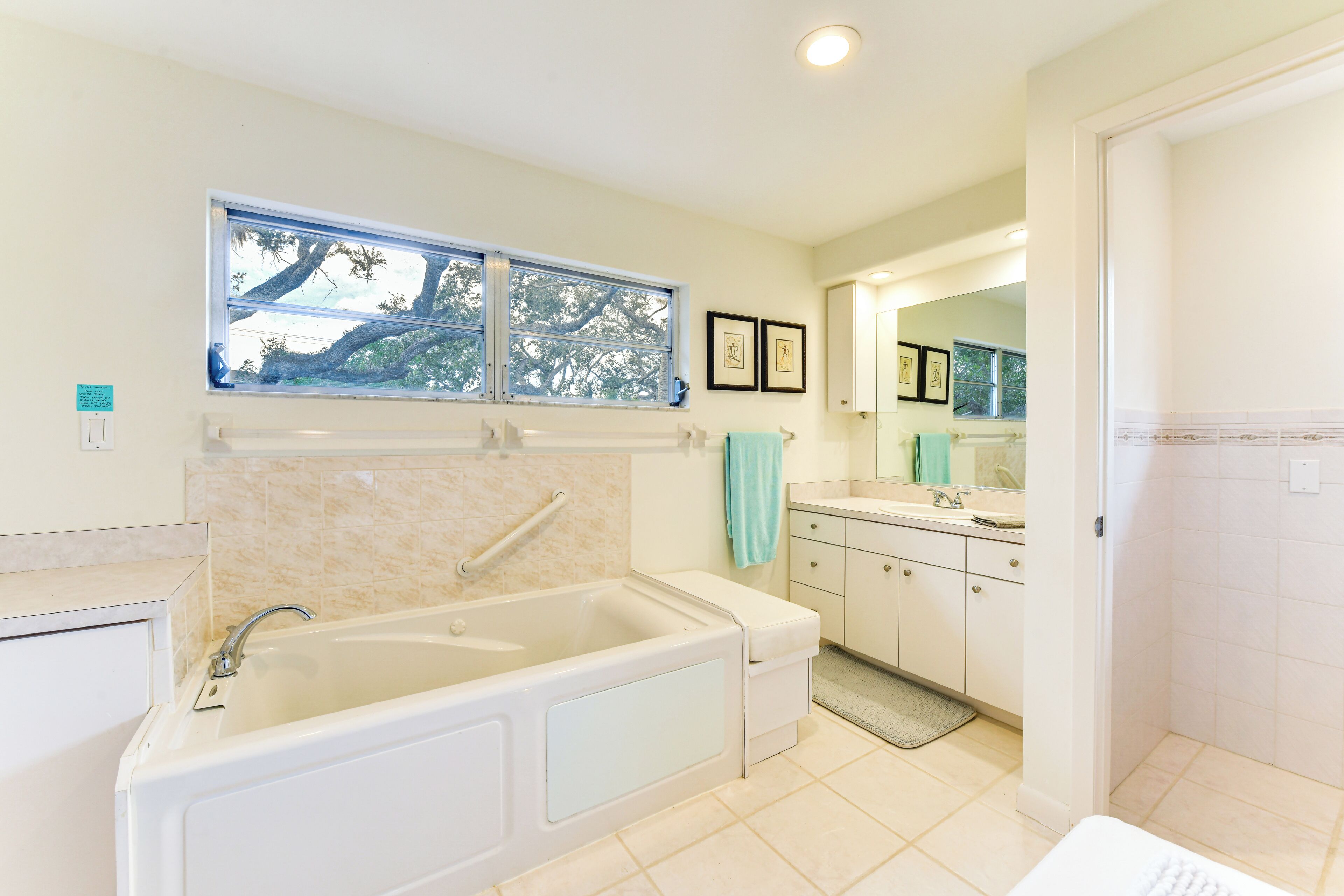 A modern bathroom with a bathtub, vanity, and a window with a view of trees.