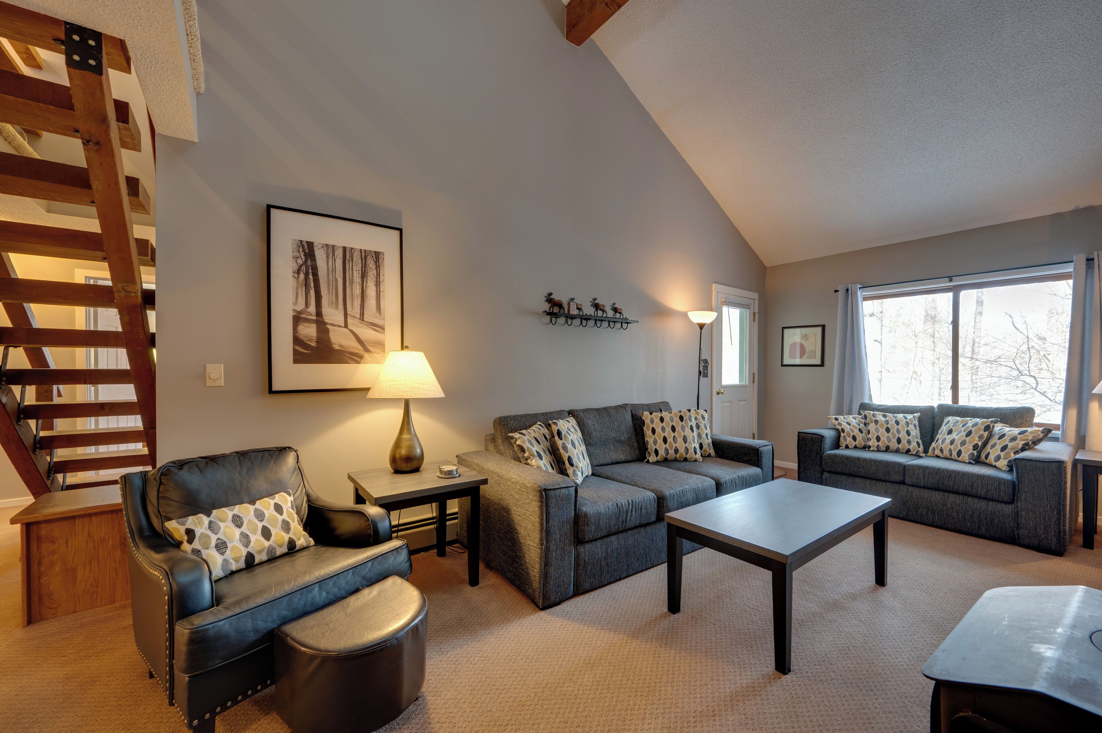 A living room with a staircase, two sofas, a coffee table, and a lamp.