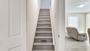 A staircase with a handrail, leading to a room with a reclining chair and a window. - Rural Bear Lake Home: 6 Mi to Lake Michigan! (Bear Lake)
