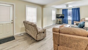 A living room with a beige sofa, a recliner, a coffee table, and a television on a stand. - Rural Bear Lake Home: 6 Mi to Lake Michigan! (Bear Lake)
