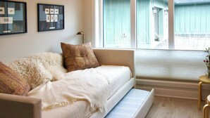 Ein gemütliches Zimmer mit Schlafsofa, kleinen Beistelltisch und Fenster mit Jalousien.
