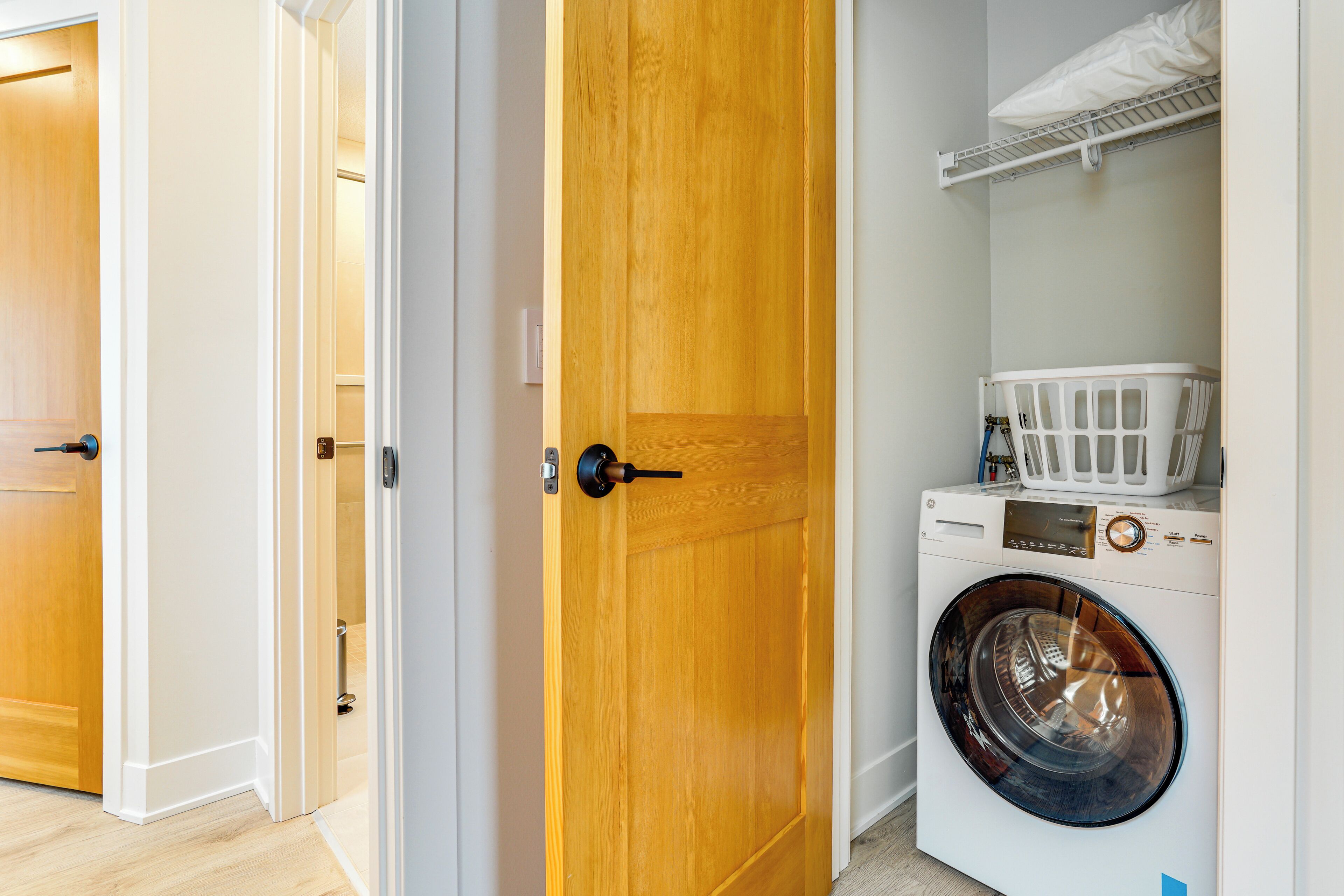 Een wasserette met een voorlader wasmachine, een droogrek en een houten deur.