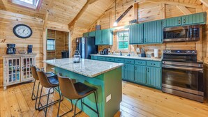 Cocina de cabaña de madera con una isla central, taburetes de bar y electrodomésticos modernos.