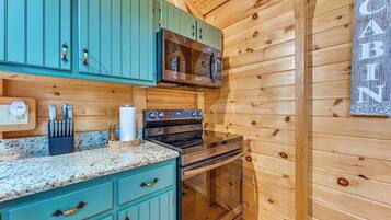 Una cocina con gabinetes color turquesa, estufa de acero inoxidable y microondas.