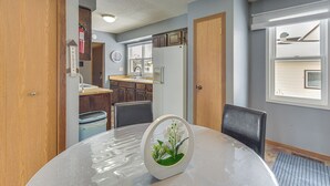 A dining table with a centerpiece, a kitchen area with cabinets and appliances, and a window with blinds. - Pet-friendly Siren Home! Walk to Bars & Lakes (Siren)
