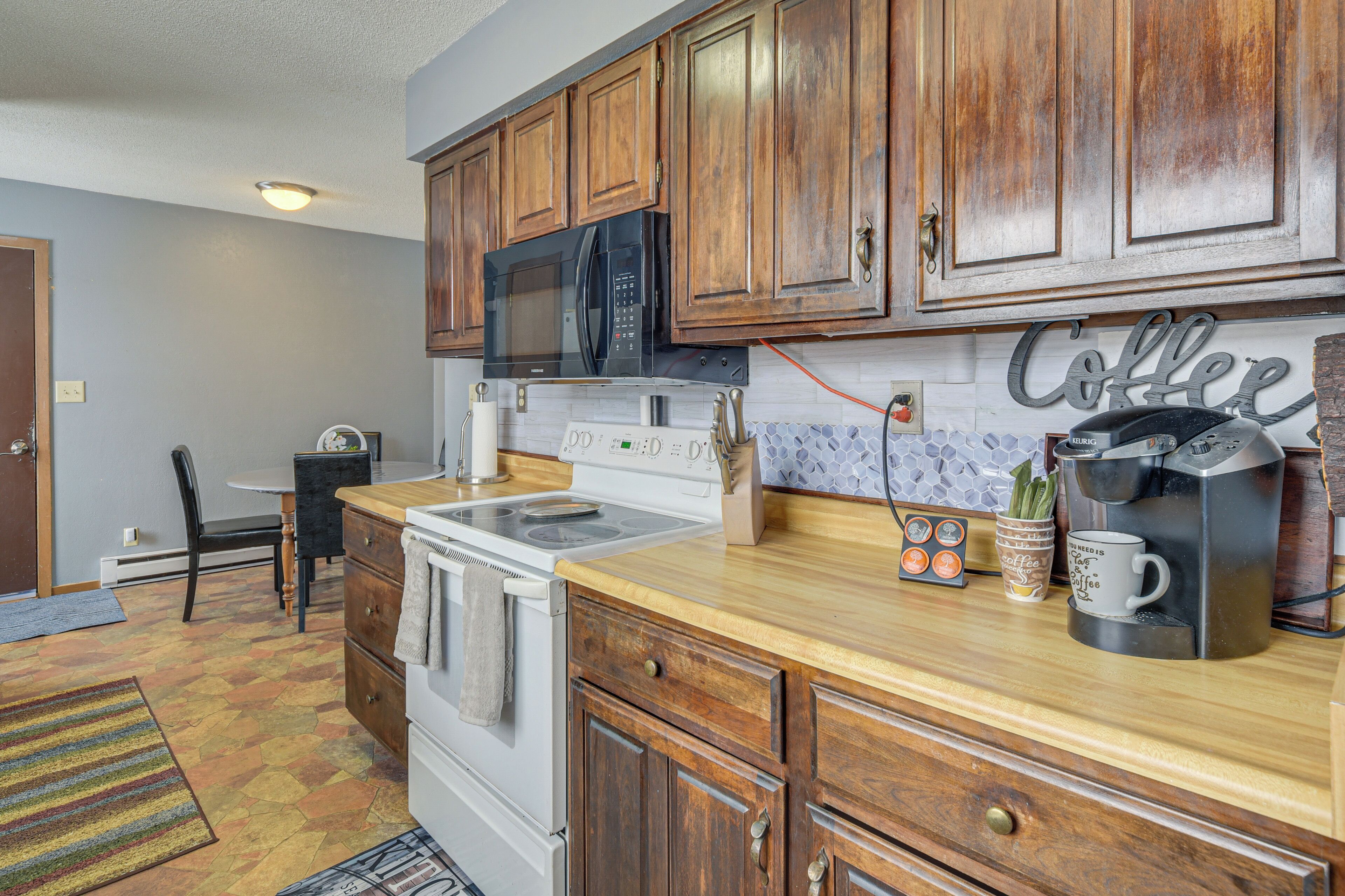 A kitchen with wooden cabinets, a microwave, a coffee maker, and a tiled backsplash.