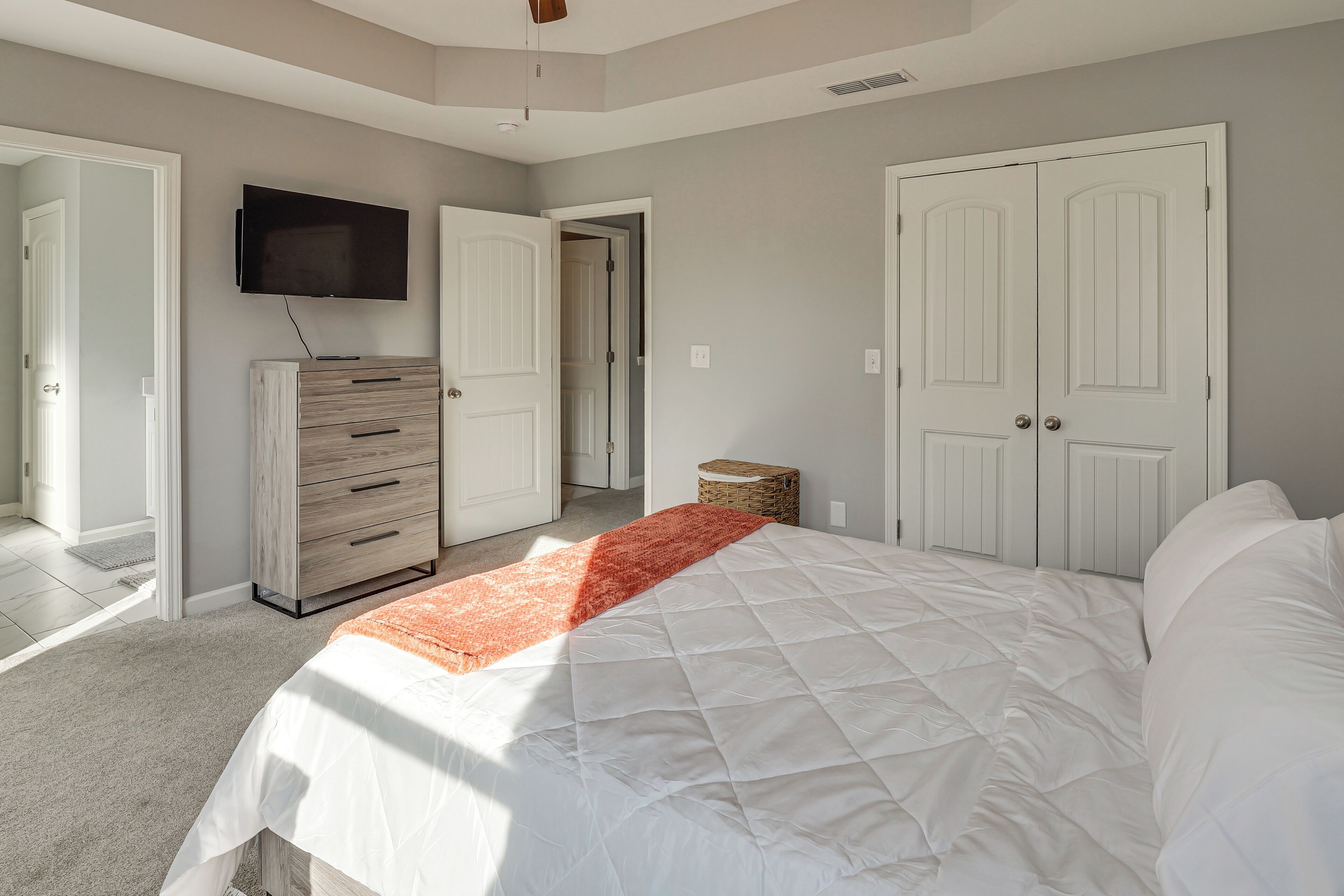 Un dormitorio con una cama, un aparador, un televisor y dos puertas.