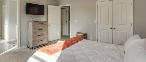 Un dormitorio con una cama, un aparador, un televisor y dos puertas.
