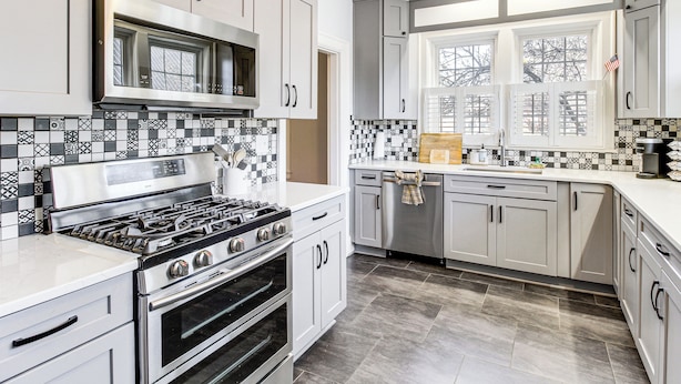 A modern kitchen with white cabinetry, a gas stove, an oven, a microwave, and a window with blinds. - Pool, Patio & Putting Green: Manchester Getaway (Manchester)