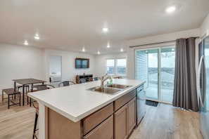 A modern kitchen with a large island, built-in appliances, and a sliding glass door leading to a balcony.
