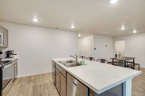 A modern kitchen with a central island, stainless steel appliances, and a dining area with a table and chairs.