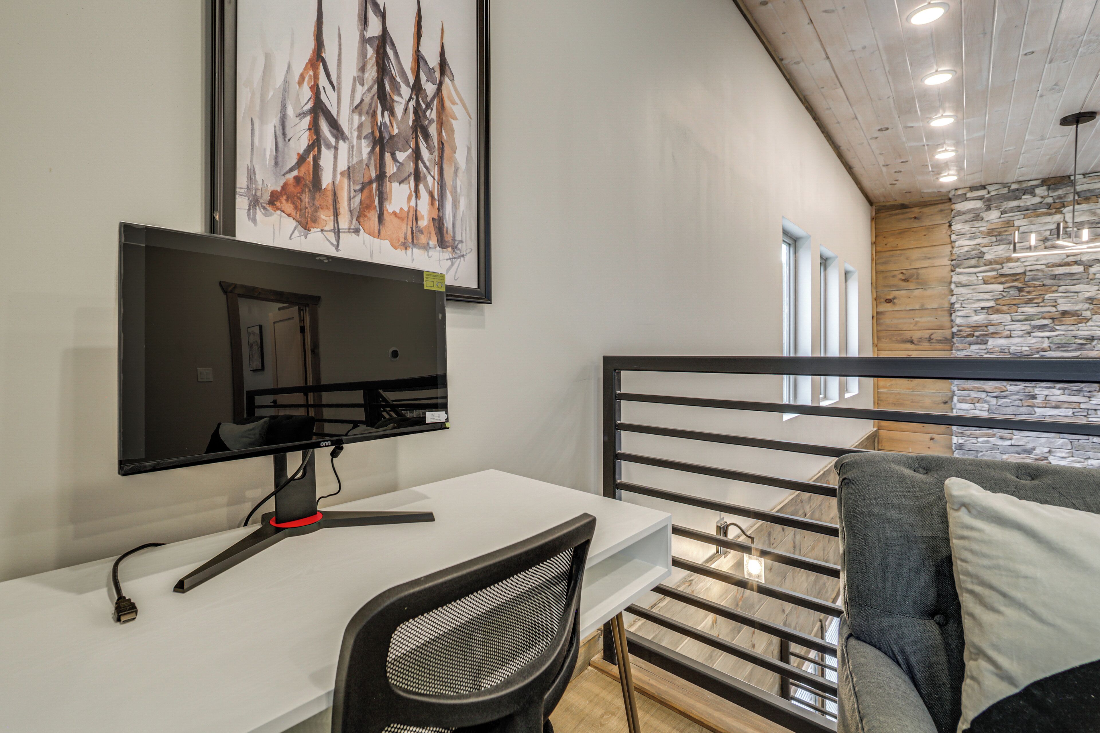 A modern room with a desk, chair, and a large framed painting on the wall.