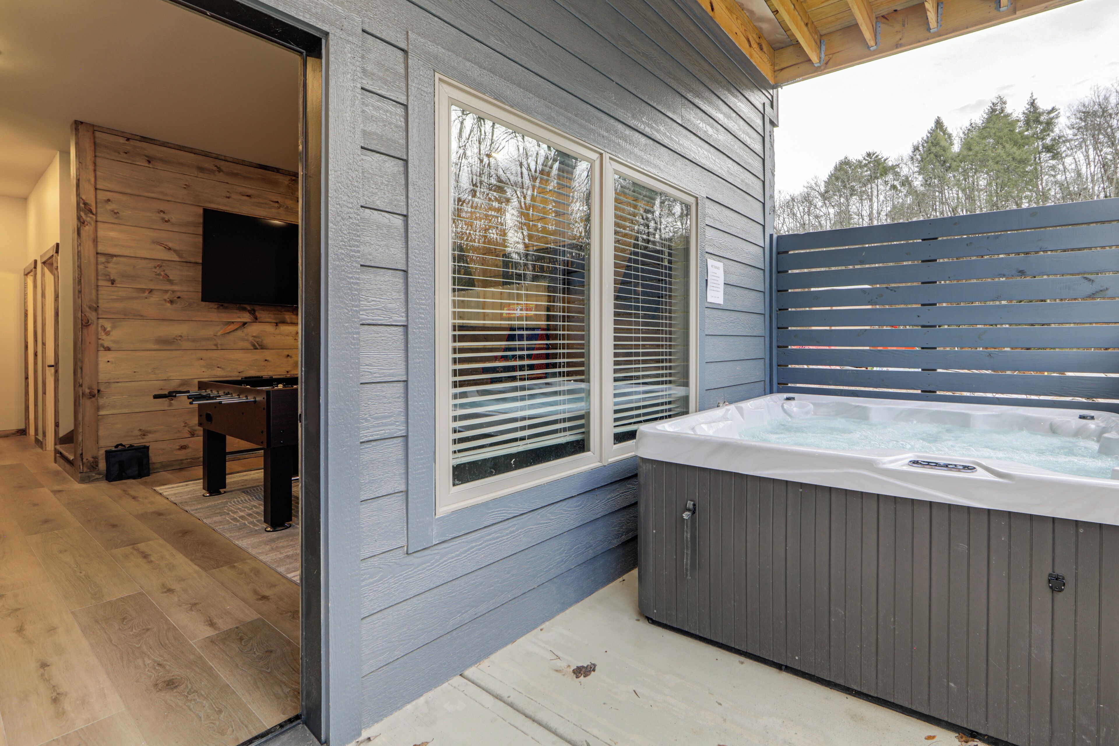 Een wellnessruimte met een jacuzzi, een houten terras en een televisie.