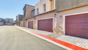 Een rij moderne herenhuizen met rode garage deuren, een heldere lucht en een rode stoeprand.