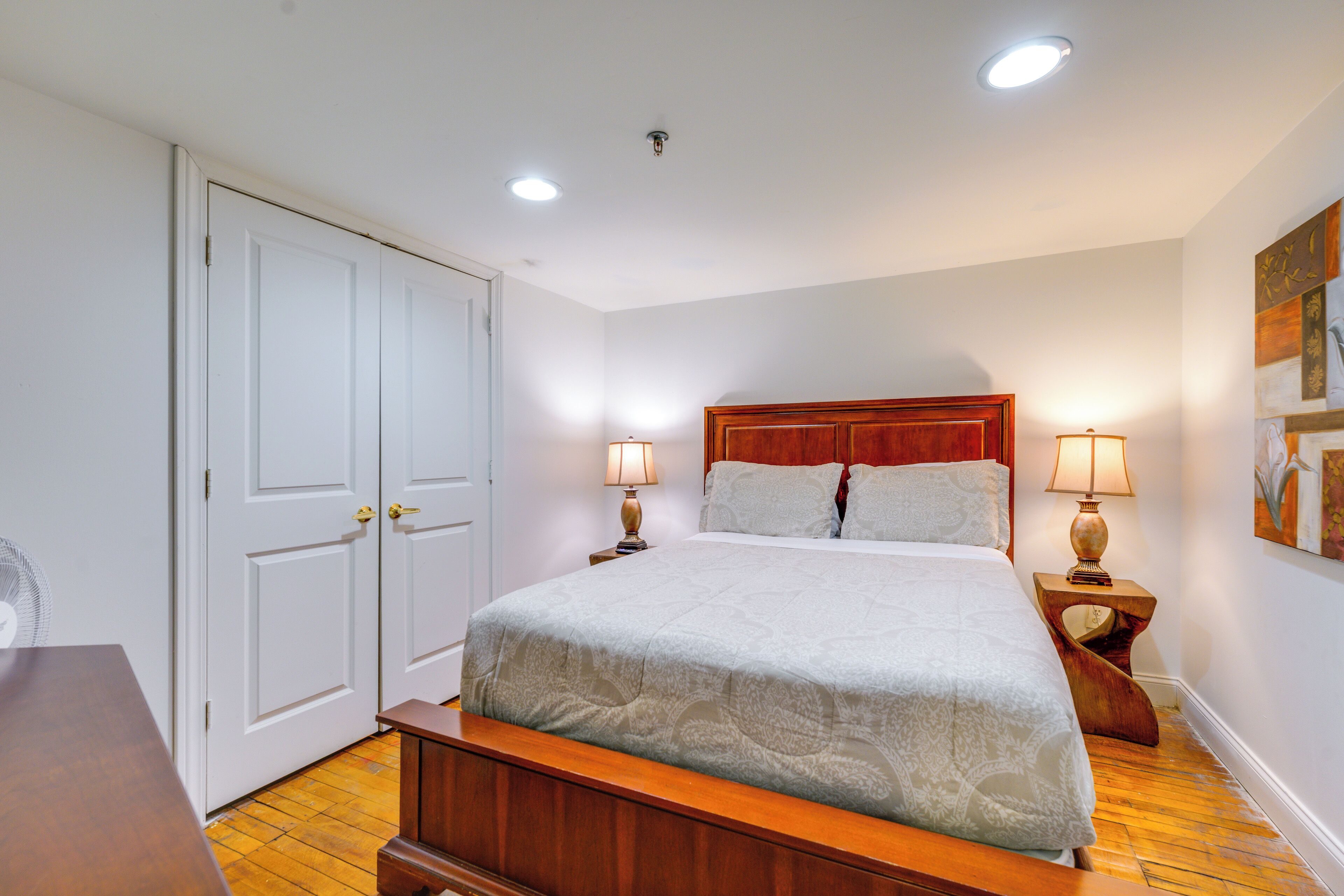 A bedroom with a wooden bed frame, two bedside lamps, and a white door.