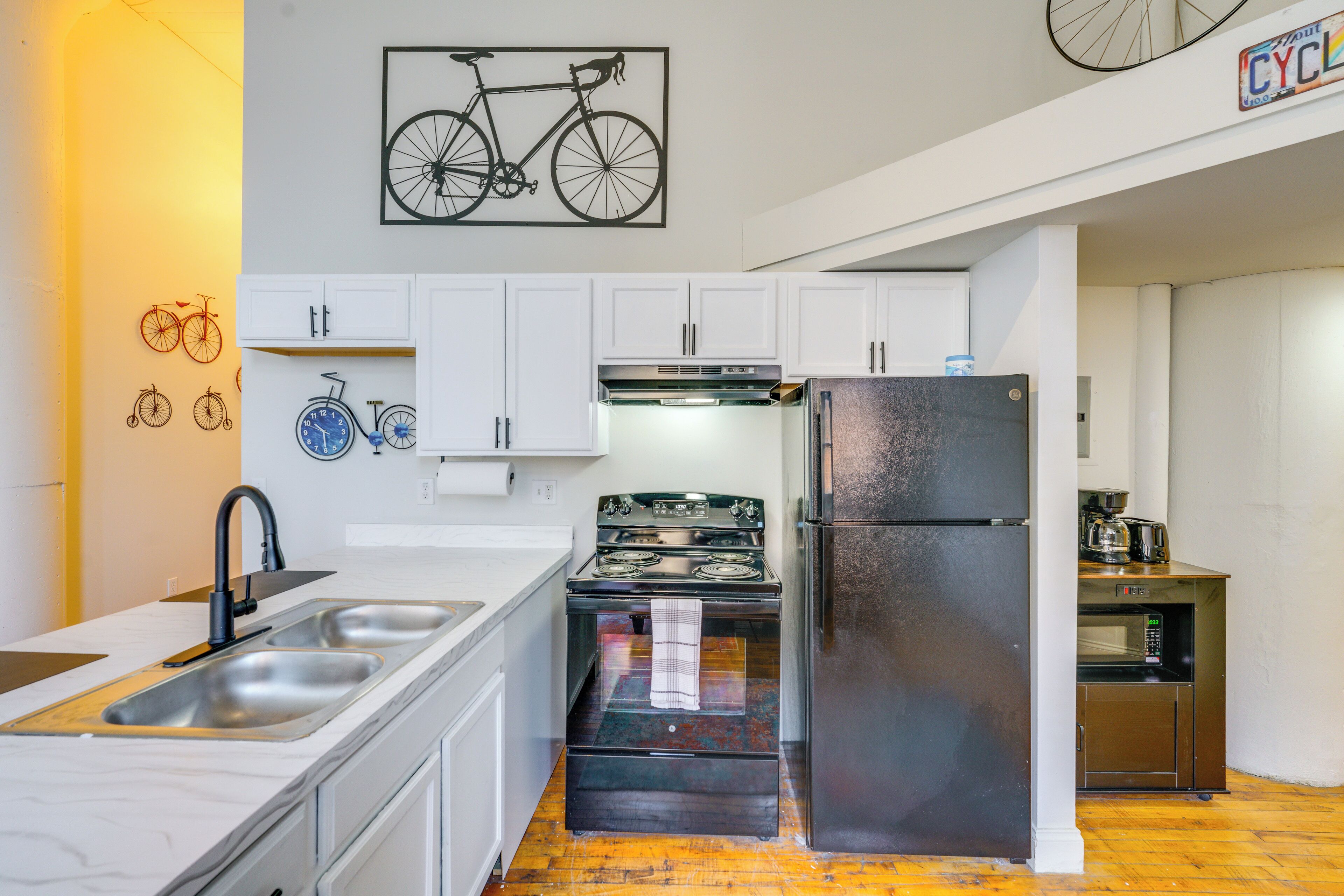 A kitchen with white cabinets, a stainless steel sink, a stove, and a refrigerator.