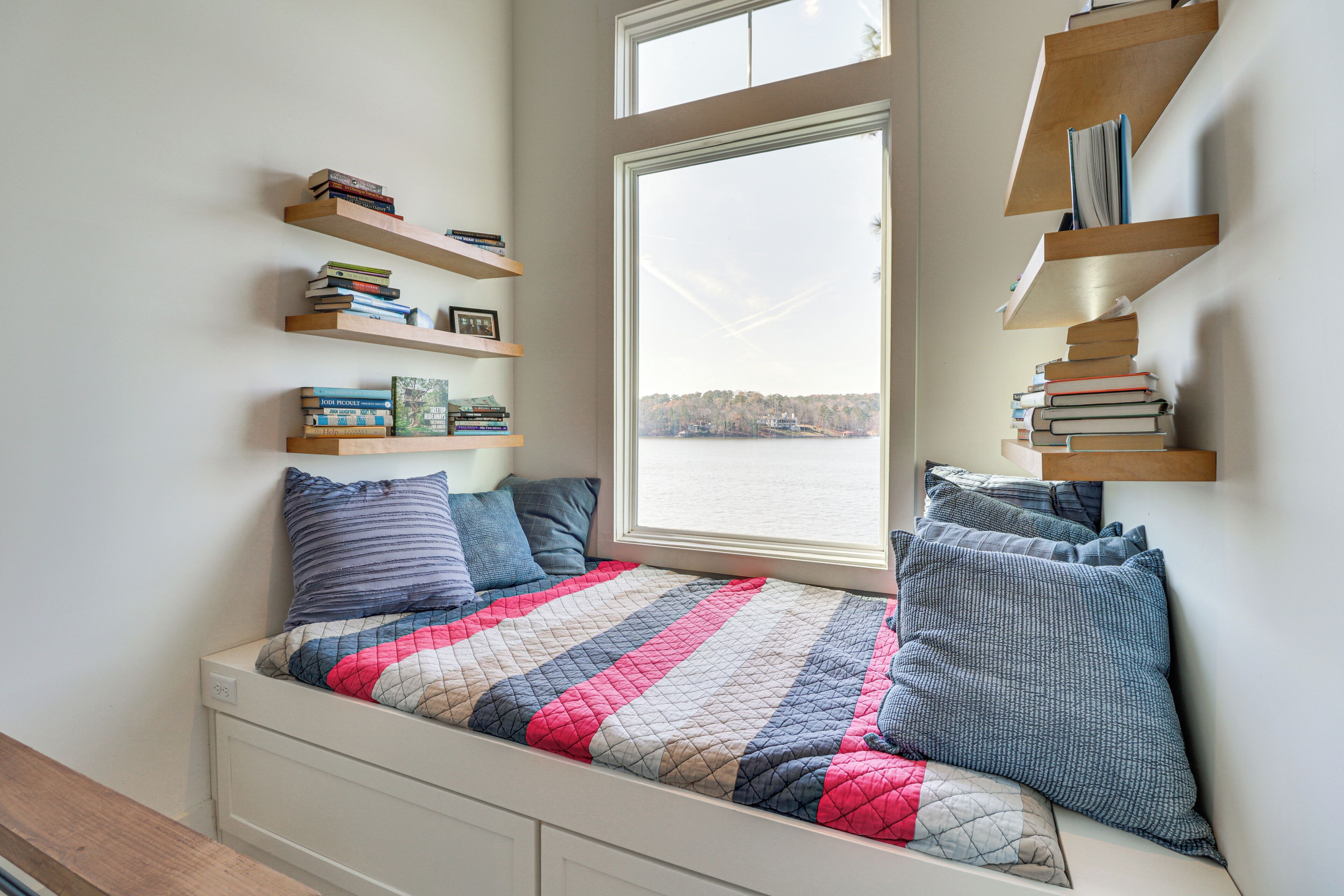 A bedroom with a bed, a window, and built-in shelves with books.